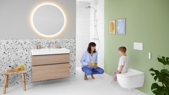 Une femme et un enfant dans une salle de bains avec un WC lavant Geberit AquaClean Alba