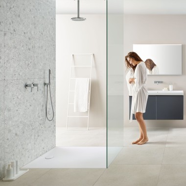 Femme dans une salle de bains avec douche à l’italienne et receveur de douche Geberit Olona