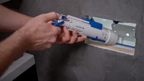 Un homme installe un mécanisme de chasse Geberit dans un réservoir à encastrer (© Ben Huggler) Un homme installe un mécanisme de chasse Geberit dans un réservoir à encastrer (© Ben Huggler)