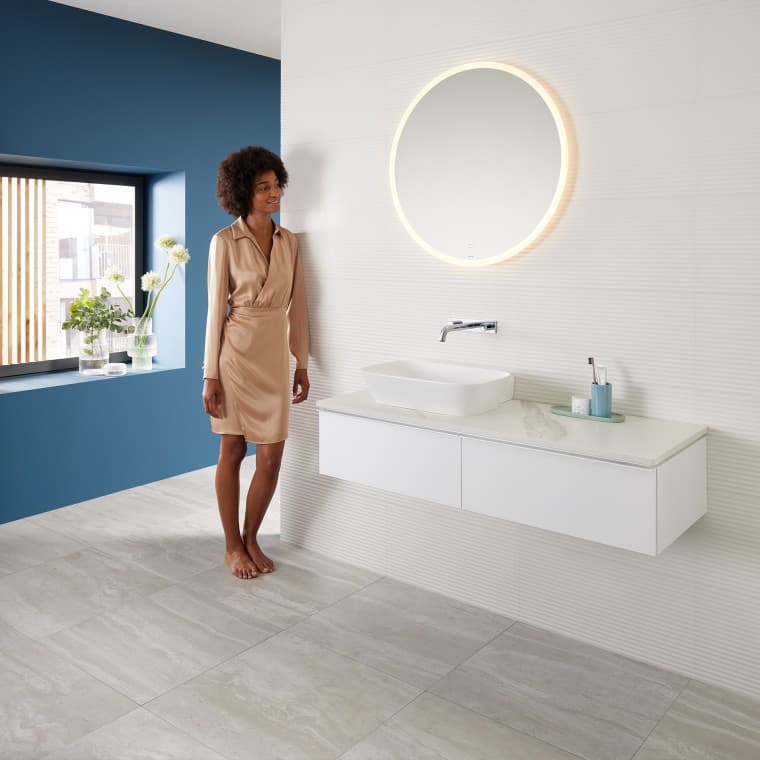 Femme adossée au mur d’une salle de bains moderne combinant des produits de la gamme Geberit Mix & Match Femme adossée au mur d’une salle de bains moderne combinant des produits de la gamme Geberit Mix & Match
